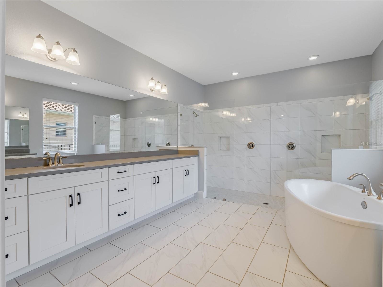 large white bathroom with glass walk in shower and soaking tub